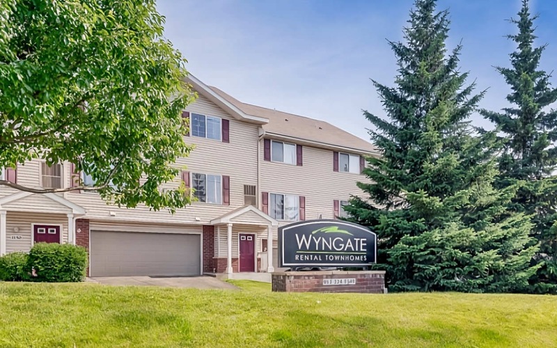 Wyngate stone sign on grassy hill with trees
