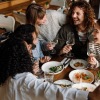 Friends laughing around a table with food